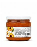 A jar of Big Bear Farms Apricot Jam with a white lid and a white label featuring illustrations of sliced apricots, photographed on a clean white background.