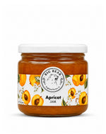 A glass jar of Big Bear Farms Apricot Jam with a white lid and a white label decorated with apricot illustrations, set against a plain white background.