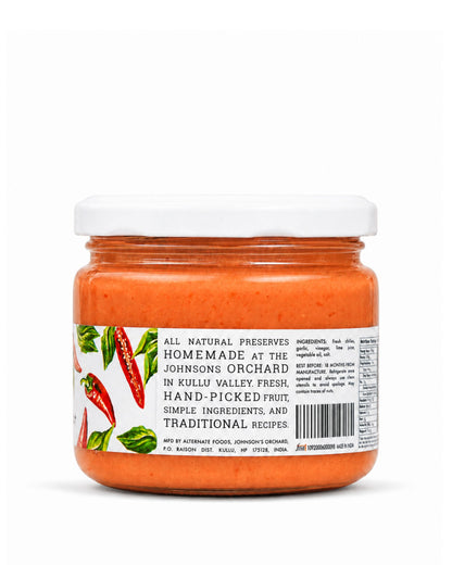 A jar of Big Bear Farms Fiery Hot sauce on a white background. The jar contains a vibrant orange-red paste and features a white lid with a label showing red chili peppers and text detailing the product's natural ingredients and hand-picked origin.