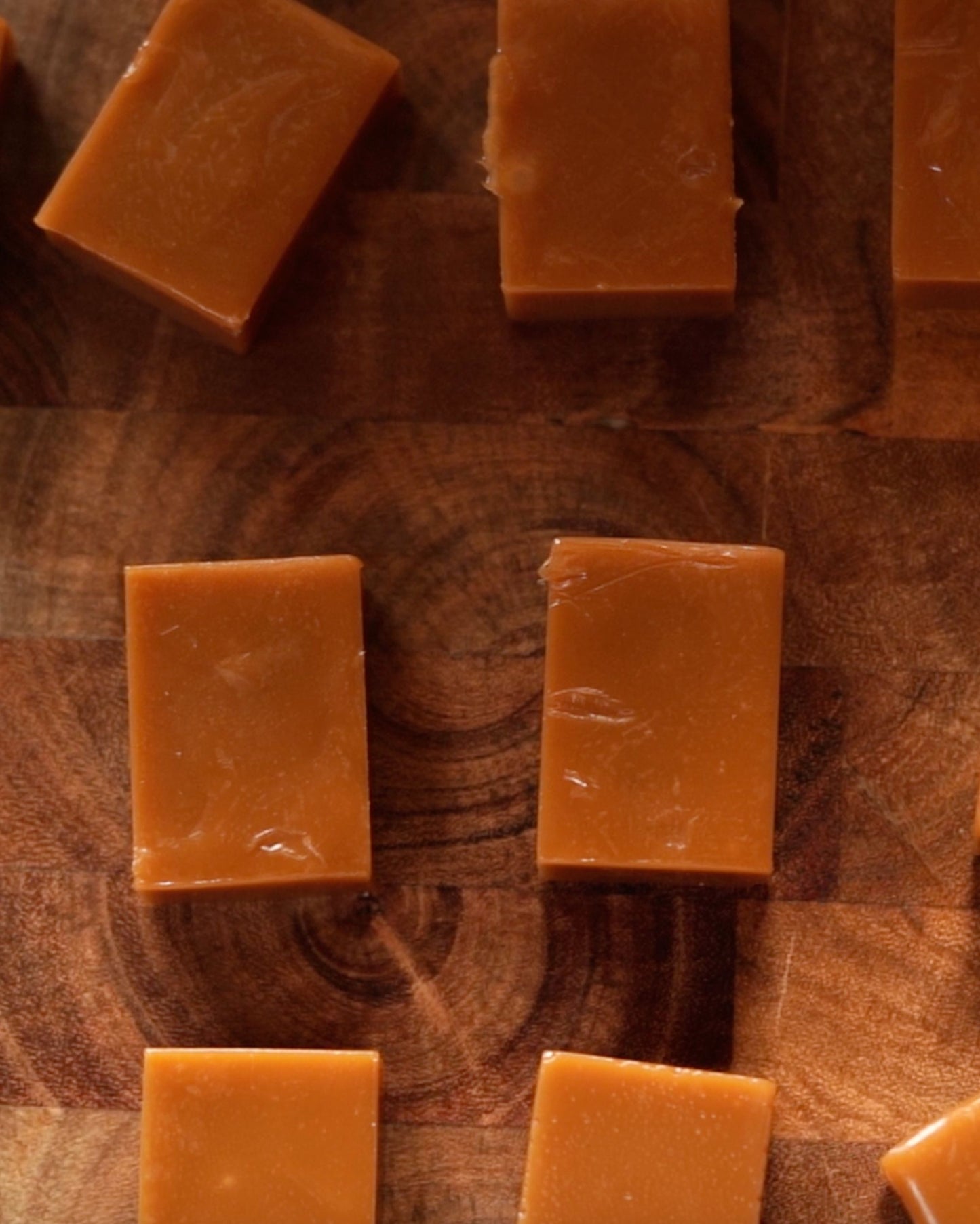Several pieces of Big Bear Farms Buttery caramel toffees arranged on a dark wooden surface.