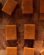 Several pieces of Big Bear Farms Buttery caramel toffees arranged on a dark wooden surface.