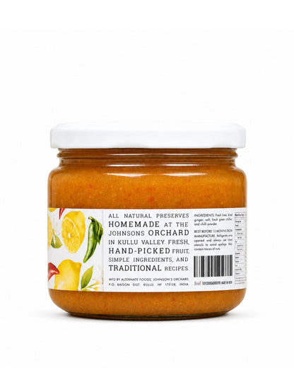 A glass jar of Big Bear Farms Homemade lemon pickle (nimbu achar) with a white lid and a white label featuring yellow and green fruit illustrations, set against a plain white background.